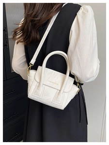 Detail of white pleated handbag with gold hardware and Fashion & Bags text on shoulder strap