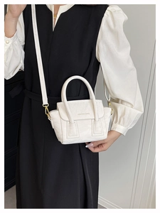 Close-up of white crossbody bag with glossy wrinkled texture and gold metal hardware
