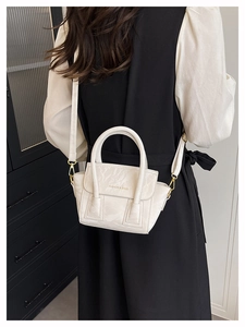 Detail of creamy white pleated leather handbag with golden metal hardware and strap