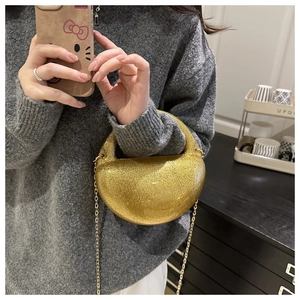 Detailed macro view of the semi-circular golden glitter clutch bag with metal chain