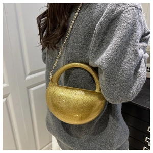 Detail of glittery gold semi-circular acrylic evening bag with chain on model