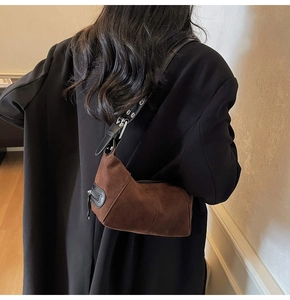 Dettaglio borsa sottobraccio in pelle scamosciata marrone con tracolla in pelle nera