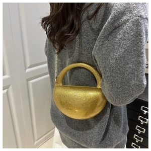 Detail of glittery gold semi-circle clutch bag with sleek metal chain and resin finish