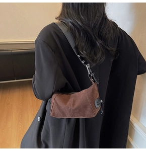 Dettaglio della borsa a spalla in pelle scamosciata marrone opaca con tracolla nera e metallo