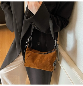 Dettaglio della borsa sottobraccio in pelle scamosciata opaca color caramello con finiture nere