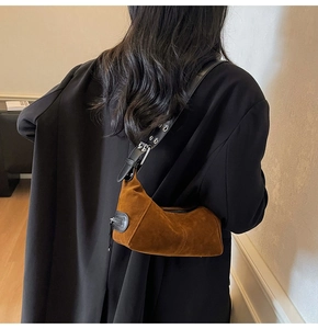 Modella che indossa borsa a mezzaluna in camoscio marrone con tracolla borchiata