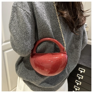 Red glitter apple-shaped acrylic evening bag with gold chain strap worn on shoulder