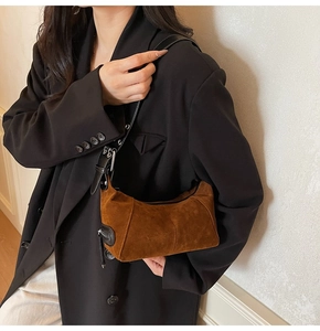 Dettaglio borsa baguette in pelle scamosciata marrone con tracolla regolabile e zip metallica