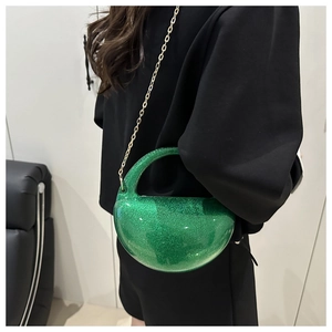 Detailed view of a crescent emerald glitter bag with gold chain strap on a model