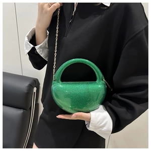 Macro detail of sparkly green acrylic spherical evening bag with gold chain strap