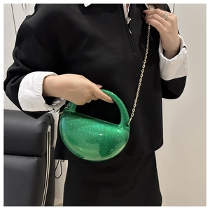 Green glitter crescent acrylic box bag with gold chain strap worn by a model