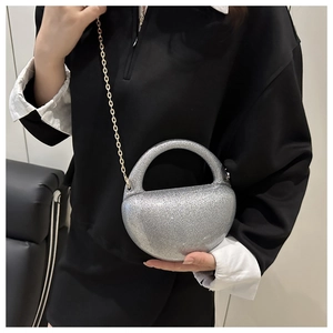 Detail of silver glitter acrylic half-moon evening bag with gold chain strap on model
