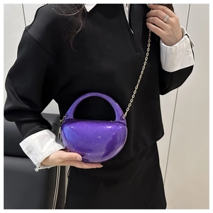 Detail of purple glitter acrylic evening bag with gold chain strap on model