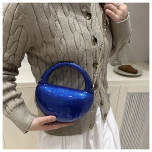 Detail of navy blue crescent evening bag with glitter finish and gold chain strap