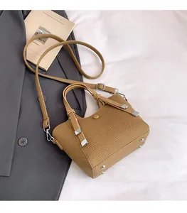 Detailed view of brown woven texture bag with silver studs and adjustable strap
