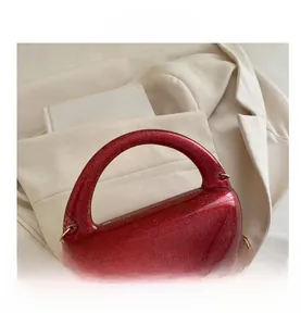 Detail of red glitter crescent clutch bag with gold chain strap on stylish background