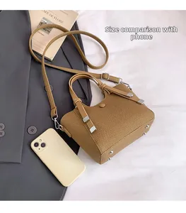 Brown woven bucket bag with long strap and handles showing size comparison to a phone