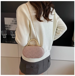 Borsa da sera rigida rosa in pizzo con catena dorata indossata da una modella
