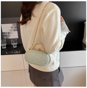Dettaglio della pochette in pizzo verde chiaro con manico dorato e chiusura a perla