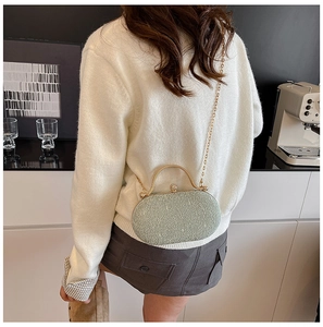 Modello con borsa da sera in pizzo verde con manico dorato e chiusura a perla