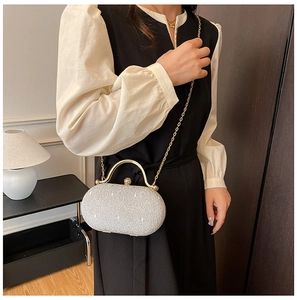 Pochette argento glitterata con manico dorato e chiusura a perla indossata da modella