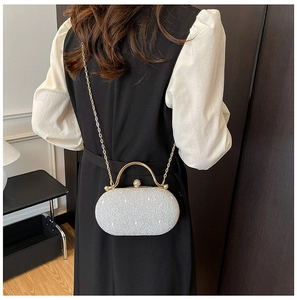 Vista posteriore di una modella con borsa da sera argento glitterata e tracolla a catena