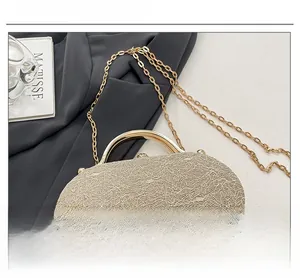 Dettaglio della pochette oro champagne con pizzo, manico in metallo e tracolla a catena