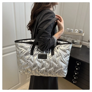 Détail du sac cabas matelassé argenté avec bandoulière noire et finition métallique