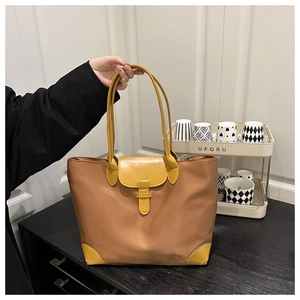Close-up of color-block tote bag featuring brown nylon fabric and yellow leather accents