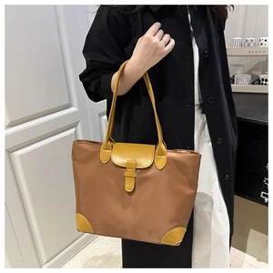Detail of contrast color large nylon tote bag with leather handles and button closure