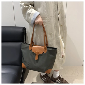 Close-up of olive green oxford tote with brown leather details and reinforced corners
