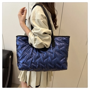 Détail du sac fourre-tout matelassé bleu marine avec des poignées en cuir noir