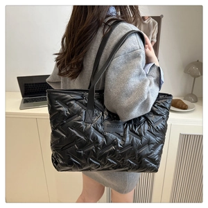 Modèle portant un grand sac cabas noir matelassé avec patch logo et bandoulière en cuir