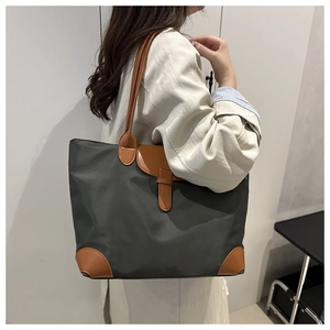 Close-up of large nylon tote bag with leather straps and reinforced corners in grey and brown