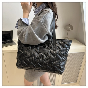 Gros plan du sac cabas matelassé noir avec écusson en cuir au design minimaliste chic