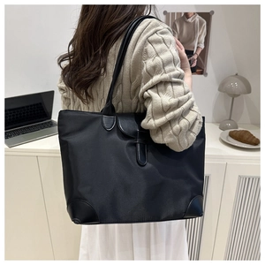Chic black tote bag shown with a model in a modern office setting for a professional look