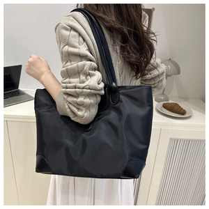 Detailed close-up of large nylon tote bag with leather reinforced corners and trim