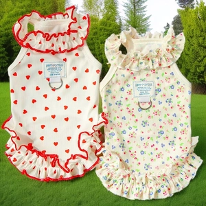 Détail de robes pour animaux à fleurs et cœurs avec volants et anneaux en D sur l'herbe