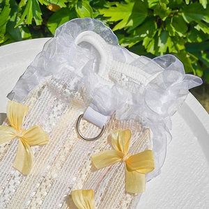 Detail of white lace pet dress with yellow bows, ruffles and metal D-ring attachment