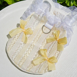 Close-up of pet lace harness with yellow bows and metal D-ring attachment for dogs