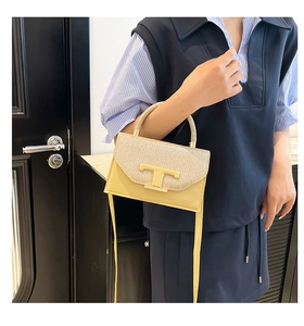 Detail of yellow leather handbag with sequined flap and golden T-shaped metal clasp