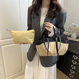 Große beige Canvas-Tragetasche mit schwarzen Lederdetails und passender Clutch-Tasche