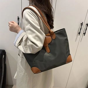 Large dark green nylon tote bag with brown leather handles worn over the shoulder