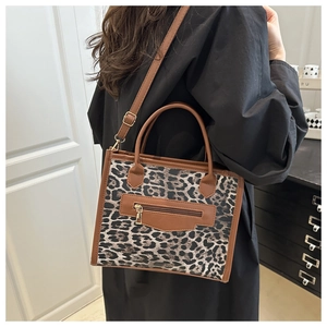 Detail of leopard print tote bag with brown leather trim and golden zipper pocket