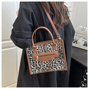 Detail of leopard print tote bag with brown leather trim and detachable shoulder strap