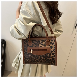 Leopard print tote bag with brown leather trim shown cross-body on a model