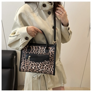 Detail of leopard print tote bag featuring black leather trim and gold-tone hardware
