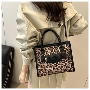 Detail of leopard print tote bag with functional front zipper and black handle