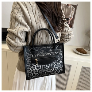 Detailed view of leopard print tote bag with black trim and detachable shoulder strap