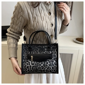 Model wearing stylish leopard print tote bag with double handles and black shoulder strap